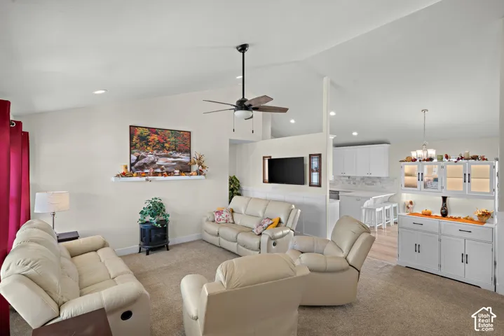 Vaulted ceilings with central fan, white built-in hutch with glass-front cabinetry, neutral carpeting, and a fireplace with a minimalist mantel