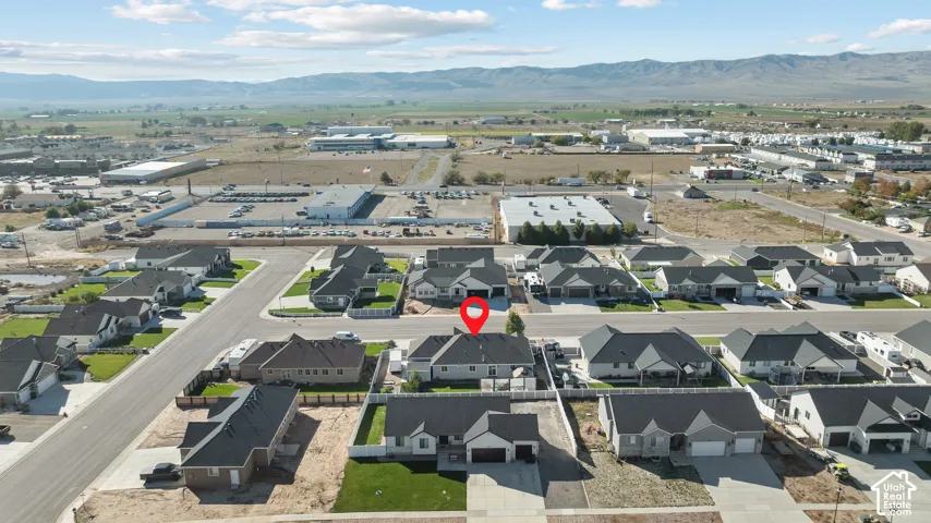 Aerial perspective of a single-story residence featuring a multi-gabled roofline, an attached two-car garage, and mountain-range backdrops