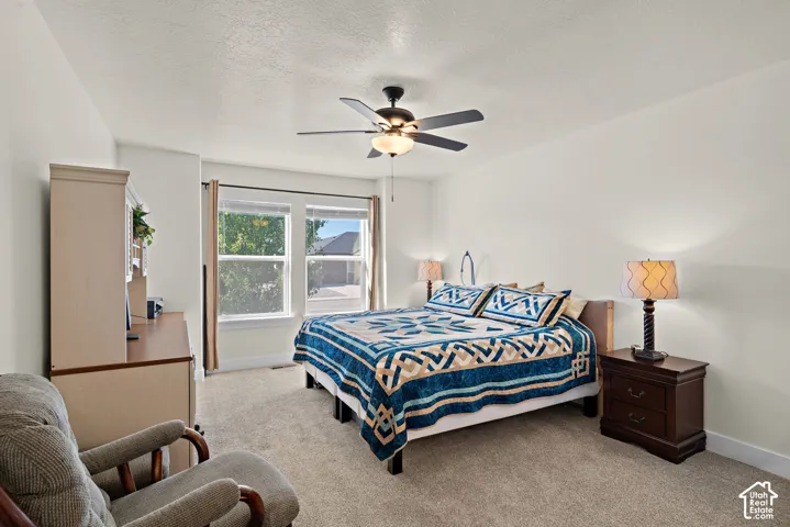 Neutral wall tones, carpeting, dual windows with blinds, and a ceiling fan with light fixture