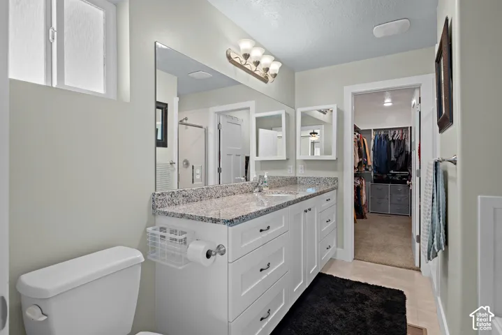 Bathroom featuring a white dual-drawer vanity with stone countertop, integrated sink, expansive wall-mounted mirror, and multi-bulb light fixture