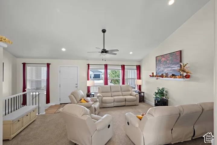 Vaulted ceilings featuring recessed lighting, a ceiling fan, multiple windows with neutral-toned trim, and a wall-mounted display shelf