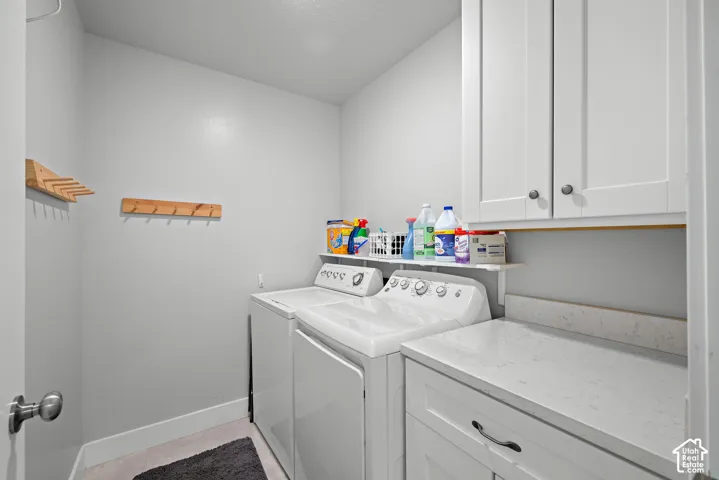 Laundry area featuring white shaker-style cabinetry, quartz countertop, and wall-mounted wooden hooks