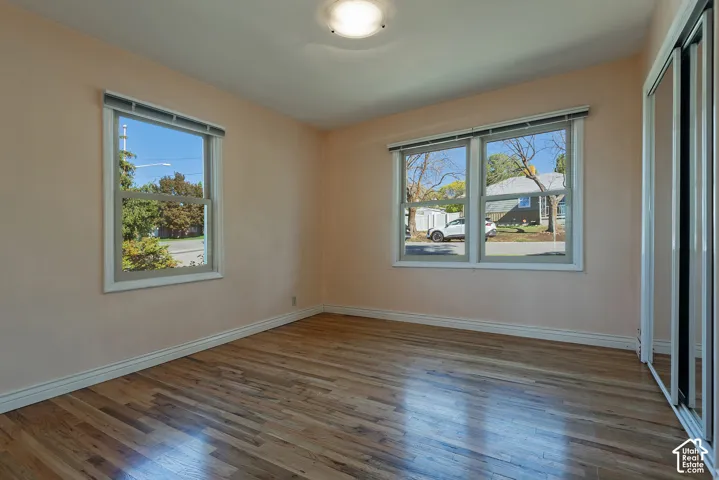 Room featuring wood-finish flooring, dual windows, and floor-to-ceiling mirrored closet doors