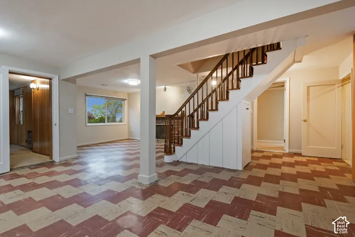 Interior space featuring patterned vinyl flooring, a wooden staircase with a baluster railing, built-in under-stair storage, and a masonry fireplace
