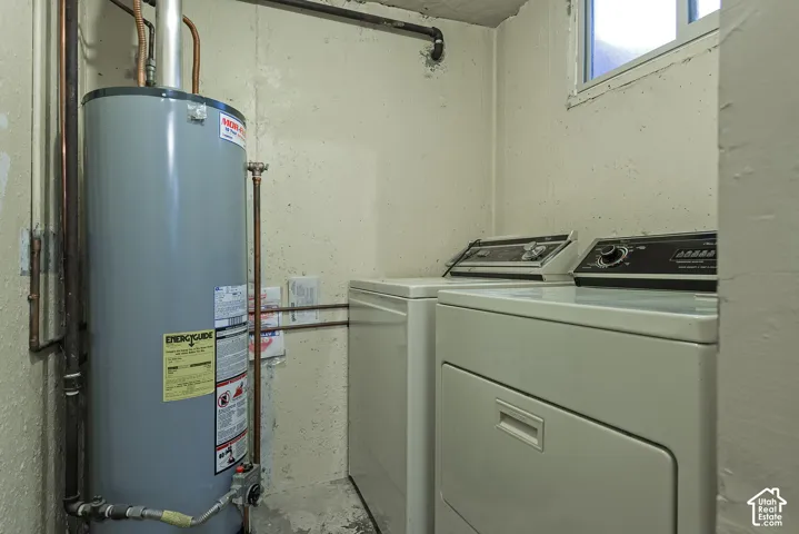 Utility space featuring a cylindrical water heater, exposed copper piping, and a laundry area with dual built-in appliances and a window
