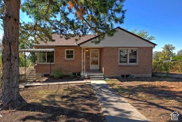 Brick exterior featuring horizontal siding, a metal-framed covered porch, metal decorative column, and concrete walkway