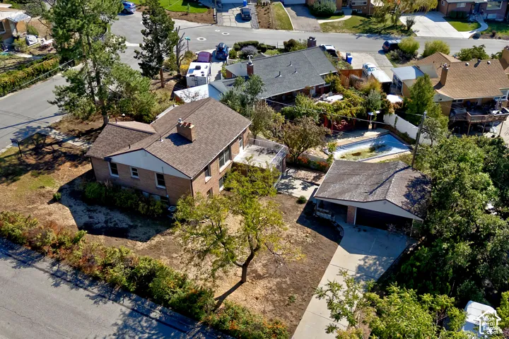 brick exterior residence featuring an asphalt shingle roof, a detached garage, a concrete driveway, and an in-ground swimming pool