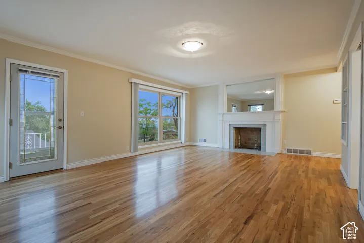 Living area featuring wood-finish flooring, a fireplace with a white mantel, an integrated wall mirror, and a glass-paneled exterior door