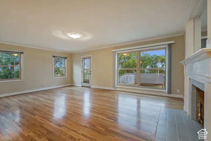 Wood-finish flooring, fireplace with a tile hearth and traditional mantel, large windows with exterior surroundings, and a glass-paneled exterior door