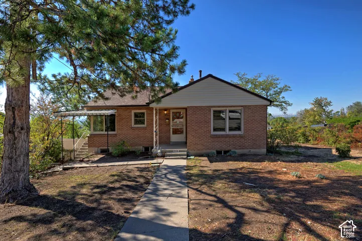 Brick exterior with horizontal siding gable, concrete front walkway, and attached metal awning