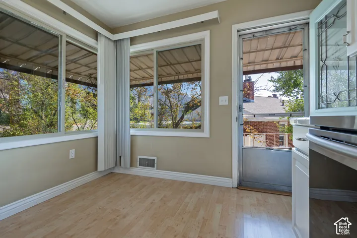 Light-filled space featuring wood-finish flooring, multiple sliding windows, and a glass-paneled storm door