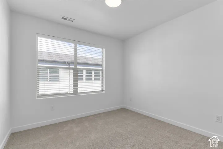 Neutral-toned wall-to-wall carpeting, window with integrated blinds, and flush-mount overhead lighting