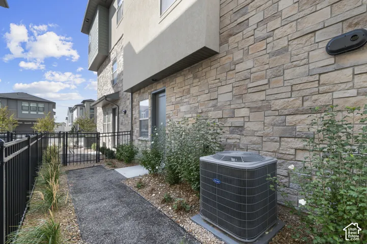Exterior featuring stacked stone veneer siding, metal perimeter fencing, and a crushed stone pathway