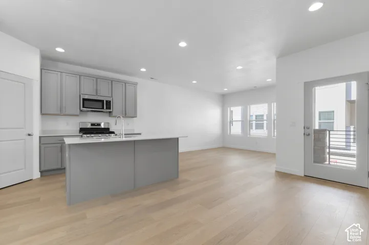 Kitchen featuring gray cabinetry, quartz countertops, a central island, recessed lighting, and wood-finish flooring
