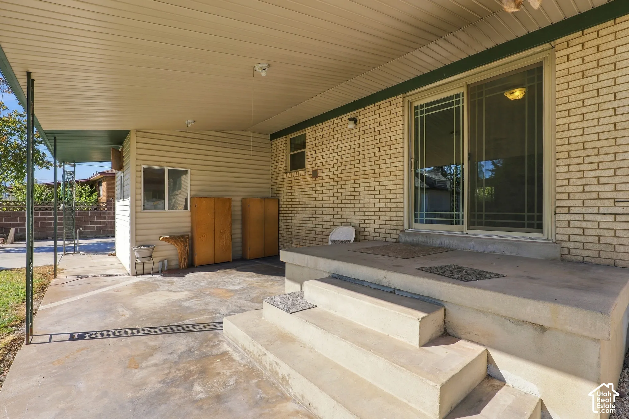 Covered concrete patio featuring brick exterior walls, siding, and sliding glass doors