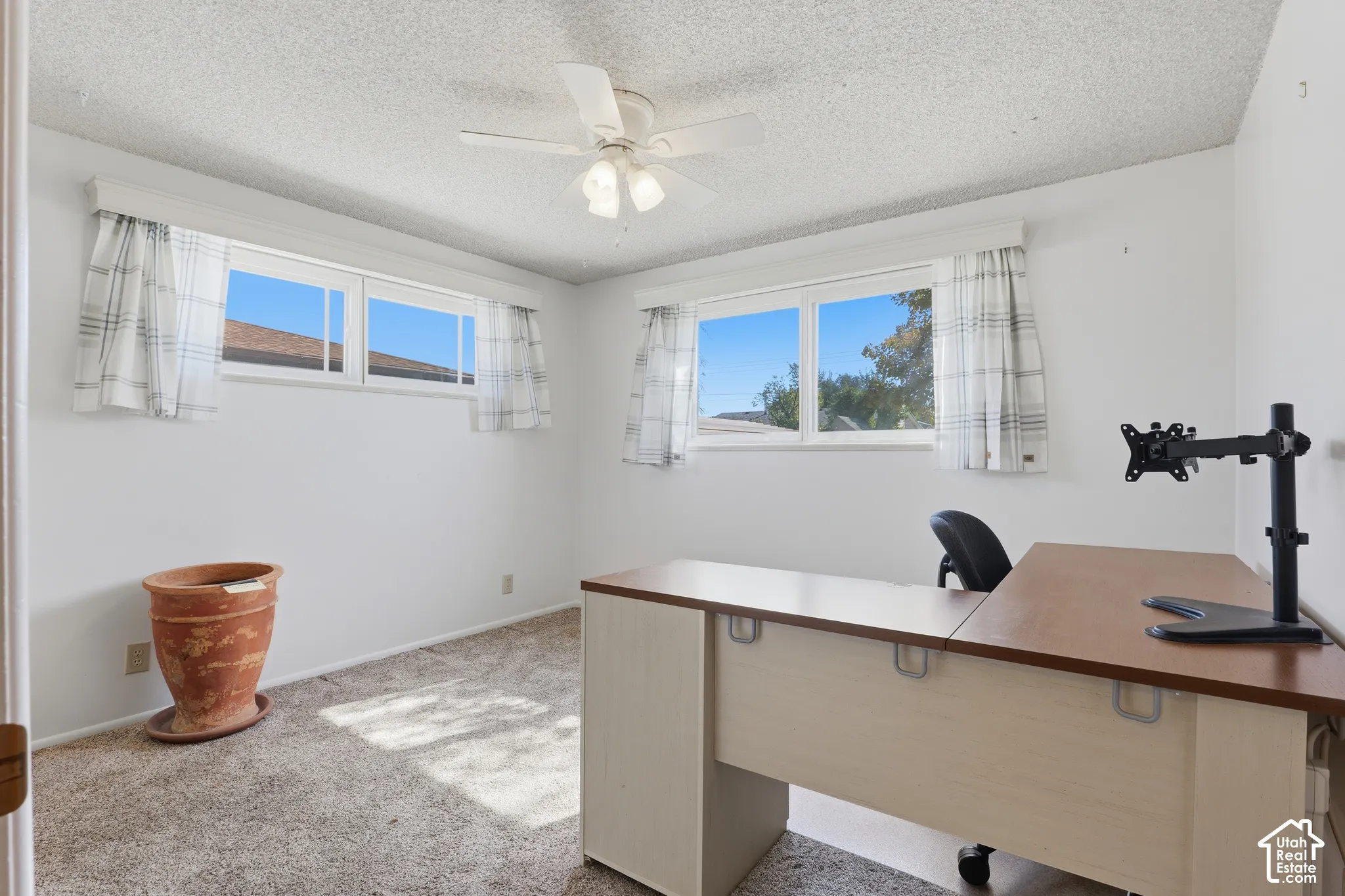 Neutral-toned interior space featuring carpeted flooring, dual-pane windows, and a ceiling-mounted light fixture with an integrated fan