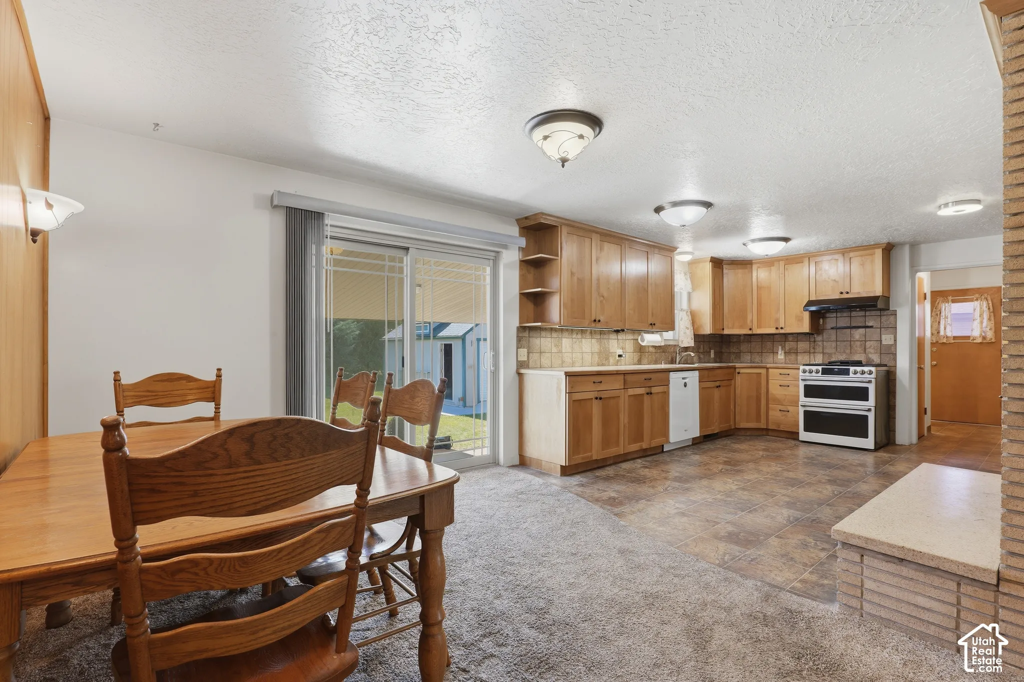 Kitchen featuring wood cabinetry, tile flooring, built-in range with hood, and sliding glass doors
