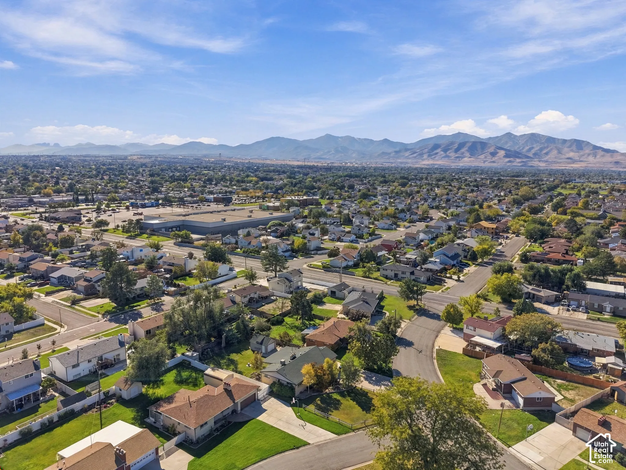 Aerial perspective featuring residential lots with mature trees and a prominent mountain range backdrop