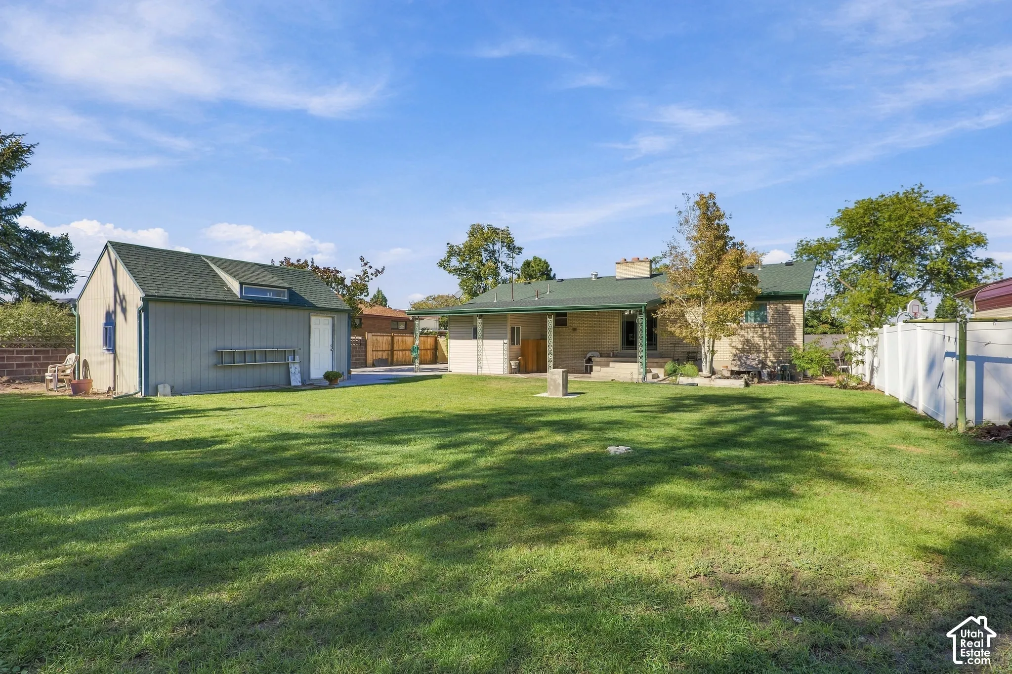 Expansive backyard featuring a manicured lawn, detached garage, covered patio, and perimeter fencing