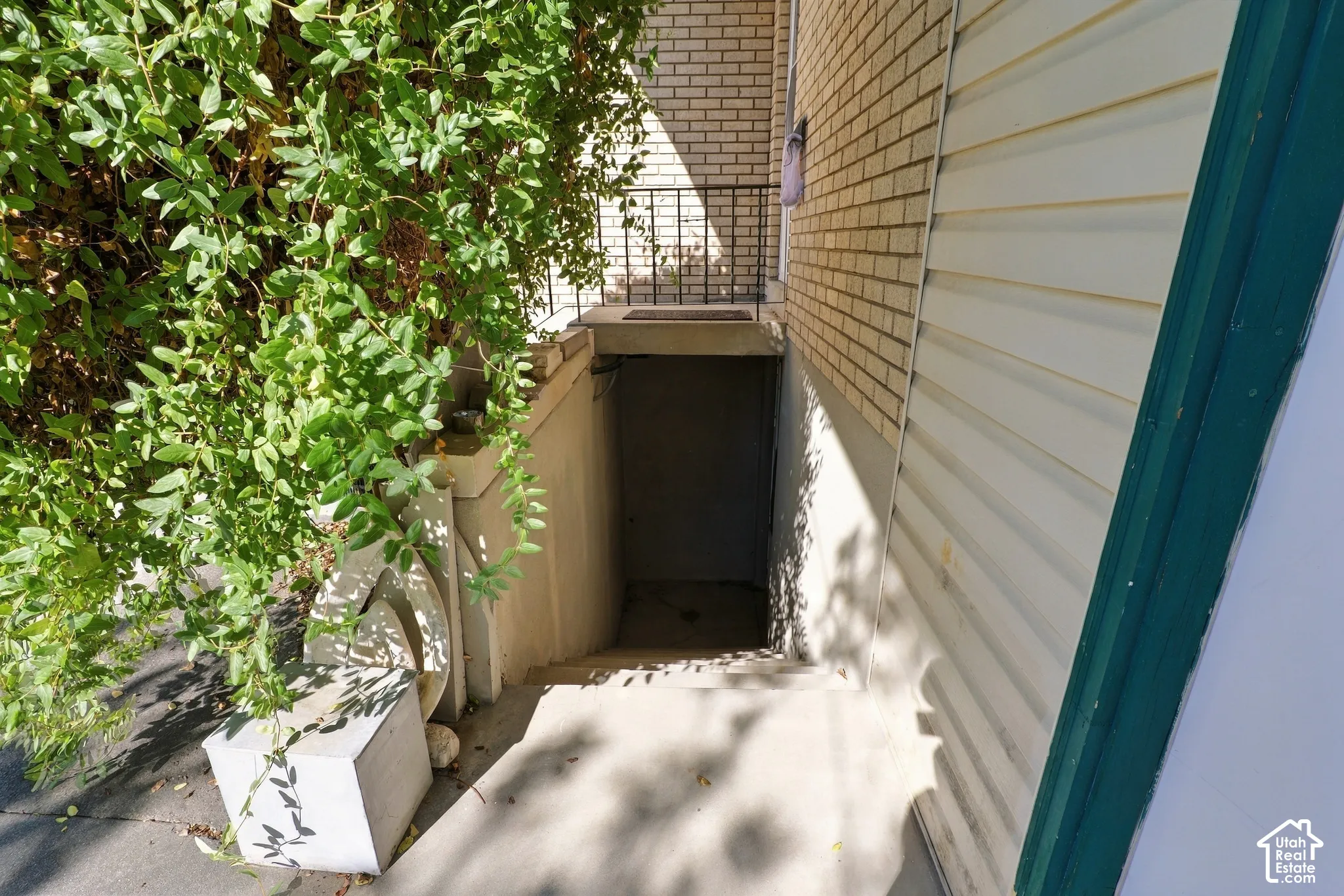 Exterior stairwell entrance featuring a brick facade, concrete steps, and a metal handrail