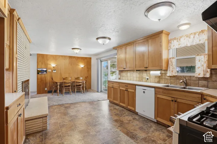 Kitchen featuring wood cabinetry, tile backsplash, laminate flooring, sliding glass door, and brick-surround fireplace