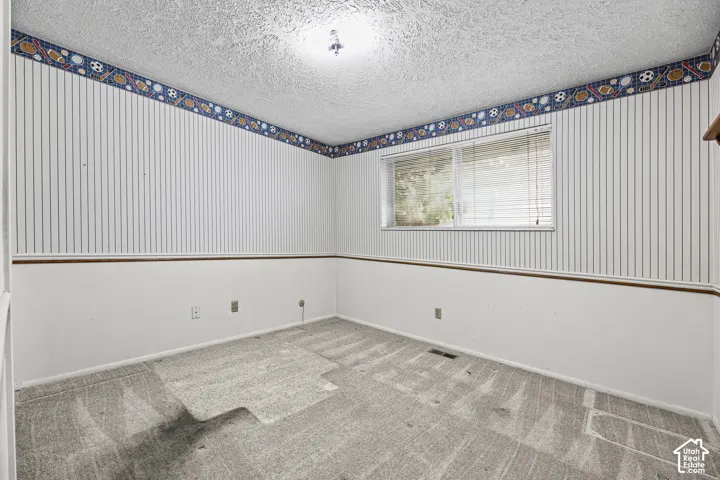 Bedroom 2- Interior space featuring textured ceiling, carpeted flooring, horizontal window with integrated blinds, and decorative wall molding