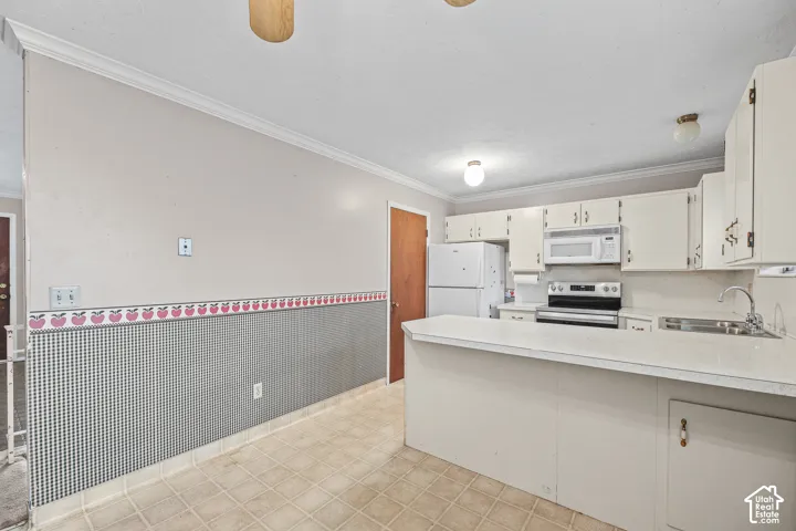 Kitchen featuring an expansive countertop peninsula, white cabinetry, integrated microwave, and neutral tile flooring