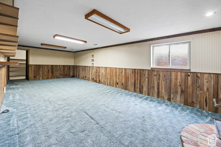 Interior space featuring wood-plank wall wainscoting, recessed lighting, a sliding egress window, and built-in wall shelving