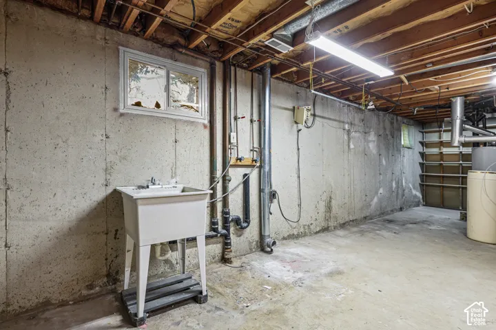 Unfinished lower level laundry room,  a utility sink, and built-in shelving
