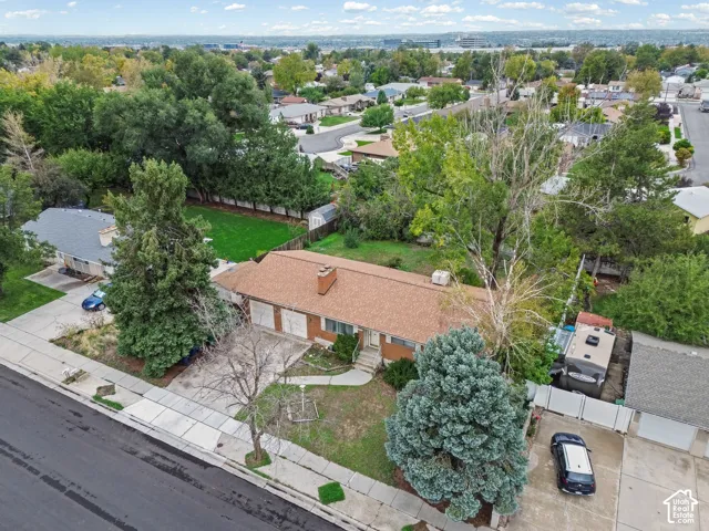 Single-level residence featuring a brick exterior, attached multi-car garage, shingled roof, mature trees, and an expansive lawn