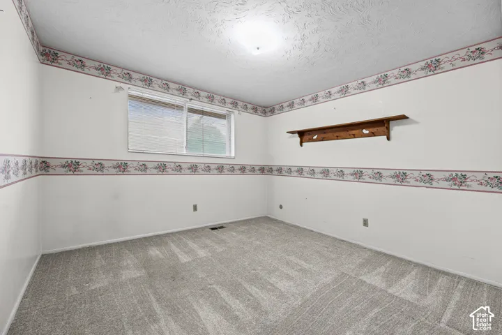 Bedroom 3- Room featuring carpeted flooring, a sliding window with horizontal blinds, and a built-in wooden wall shelf