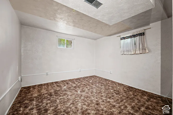 Interior room featuring textured walls, patterned carpeting, and two windows