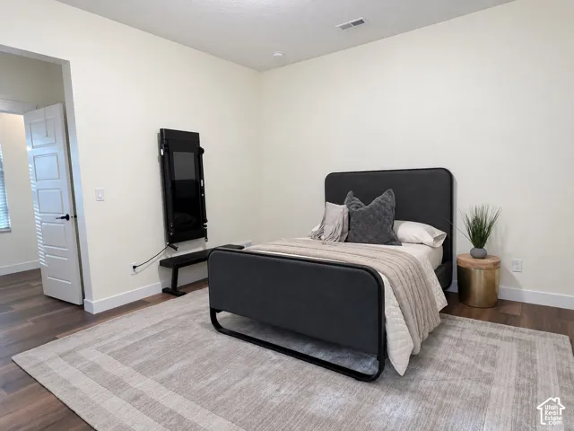 Spacious room featuring wood-finish flooring and a multi-panel interior door