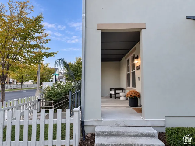 Covered entryway featuring light-toned smooth siding, concrete steps, a dark-finished ceiling, and a wall-mounted exterior light fixture