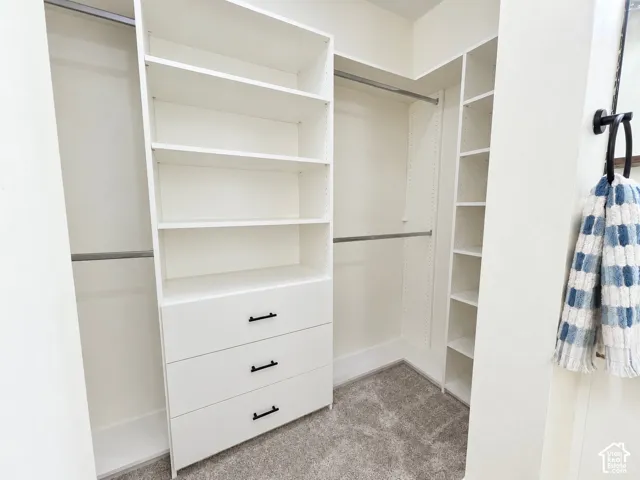 Walk-in closet featuring white built-in shelving, integrated dresser drawers with matte black hardware, and double-tier metal hanging rods