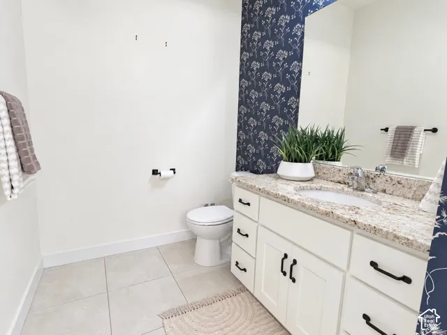 Vanity featuring stone-finish countertop, undermount sink, white cabinetry with matte black hardware, and floral patterned accent wall