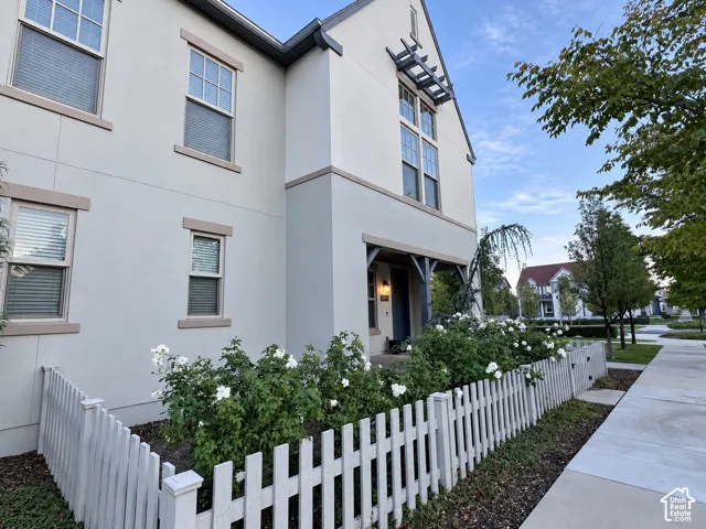 Stucco exterior featuring a white picket fence, covered porch entry, and architectural pergola detail