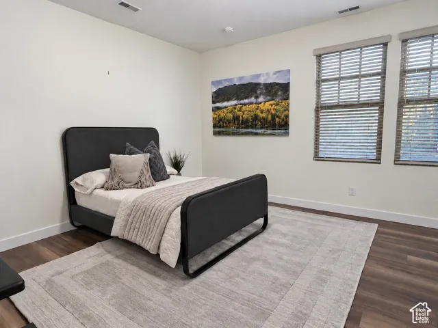 Room interior featuring wood-finish flooring and double windows equipped with horizontal blinds
