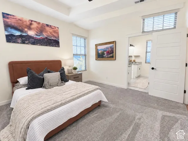 Bedroom featuring a tray ceiling, neutral wall coloring, carpeted flooring, and a five-panel interior door with matte black hardware