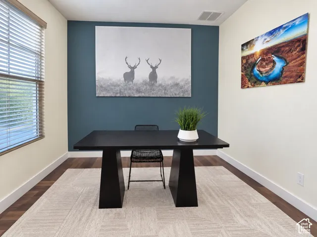 Room featuring wood-finish flooring, a bold blue accent wall, and a large window with fitted blinds