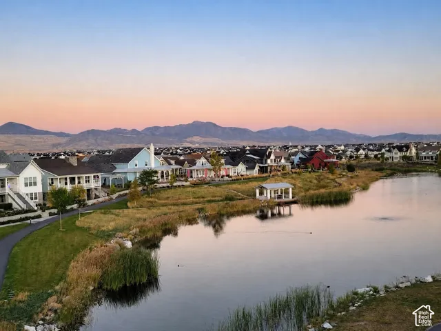 Aerial landscape featuring a reflective pond, waterfront gazebo, manicured pathways, and mountain backdrop