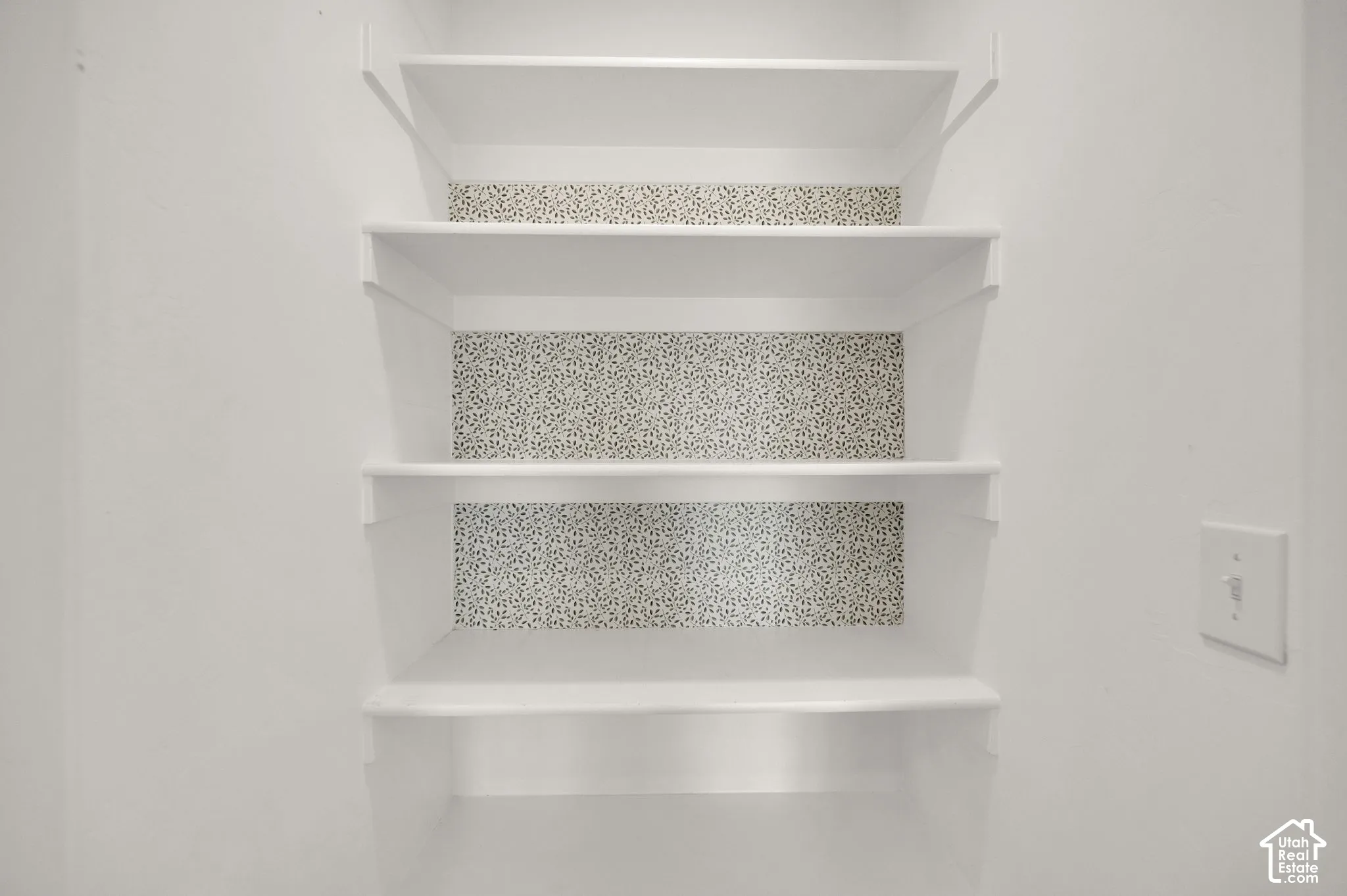 Built-in white shelving featuring patterned wallpaper backing
