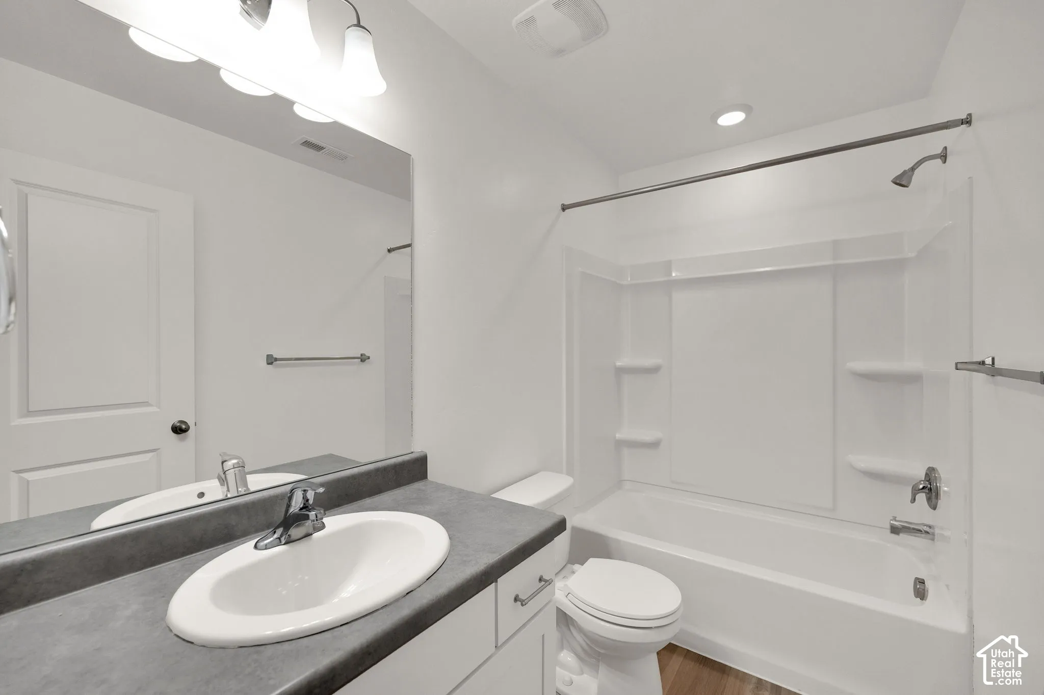 Full bathroom featuring a white vanity with a matte countertop, integrated oval sink, wall-mounted mirror, and a tub-shower combination with built-in shelving