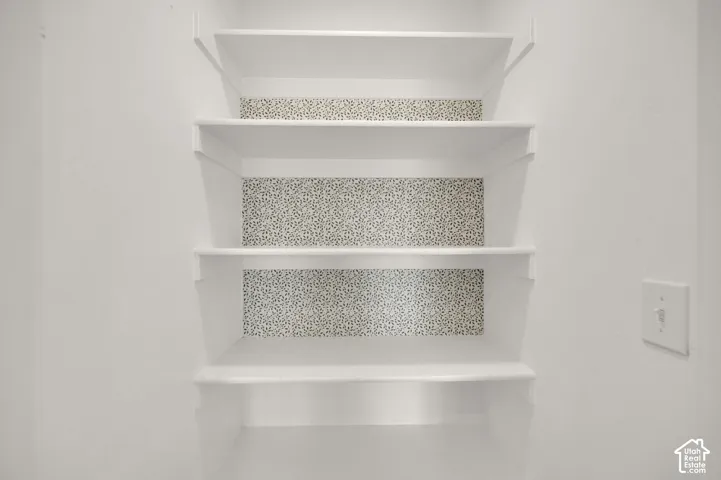 Built-in white shelving featuring patterned wallpaper backing