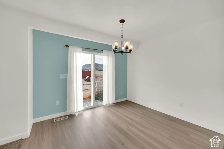 Sliding glass doors, wood-finish flooring, accent wall, and a multi-arm metal chandelier