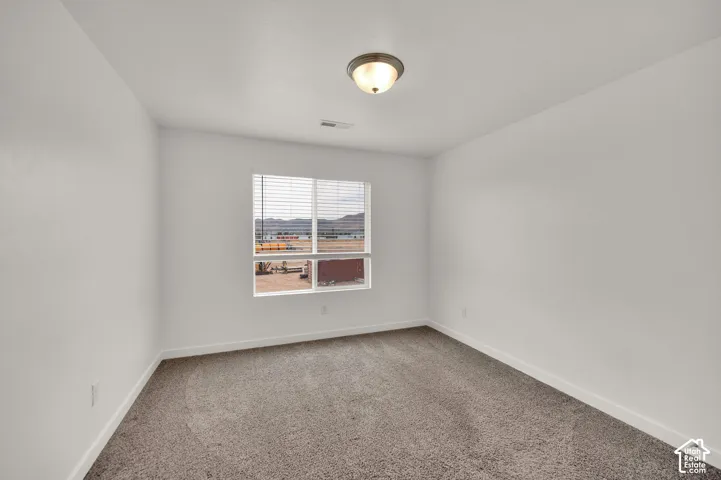 Neutral-toned interior space featuring wall-to-wall carpeting, a multi-pane window with blinds, and a dome-style flush mount ceiling light fixture