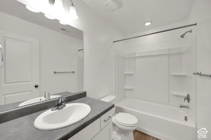 Full bathroom featuring a white vanity with a matte countertop, integrated oval sink, wall-mounted mirror, and a tub-shower combination with built-in shelving