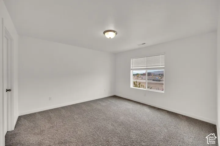 Neutral wall finish, wall-to-wall carpeting, window with integrated blinds, and a flush-mount overhead light fixture