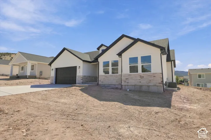 Single-story exterior featuring light-toned masonry veneer, dual-gabled roofline, attached two-car garage, and neutral stucco siding