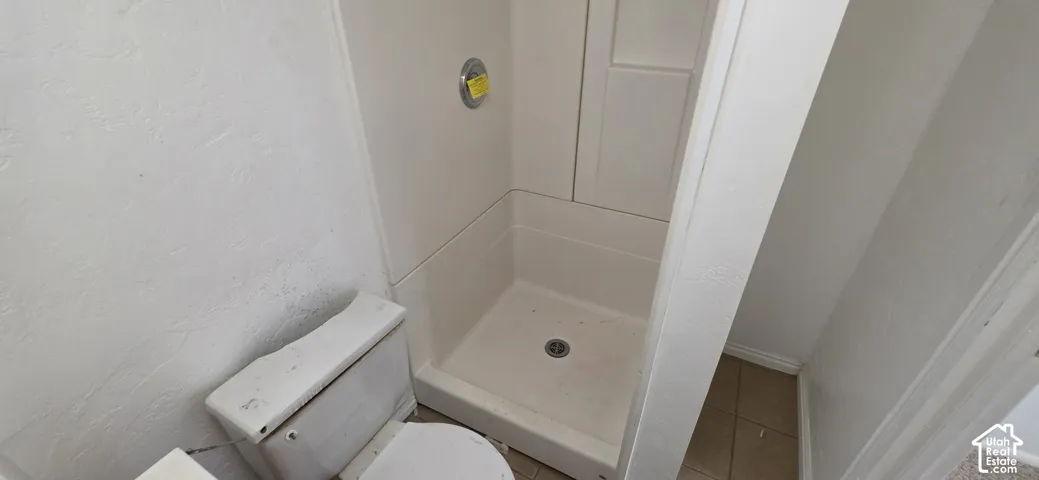 Full bathroom featuring a shower stall with surround and a standard-height toilet